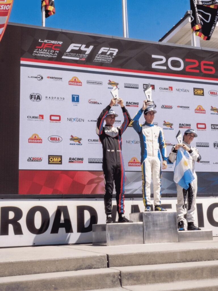 Another Podium for Berg Racing as Young Drivers Continue Strong Development at Road America 3 AJ Abdullah stands on the top step of the podium holding the first-place trophy, celebrating his victory at the 2026 Road America F4 championship race alongside the second and third-place drivers.