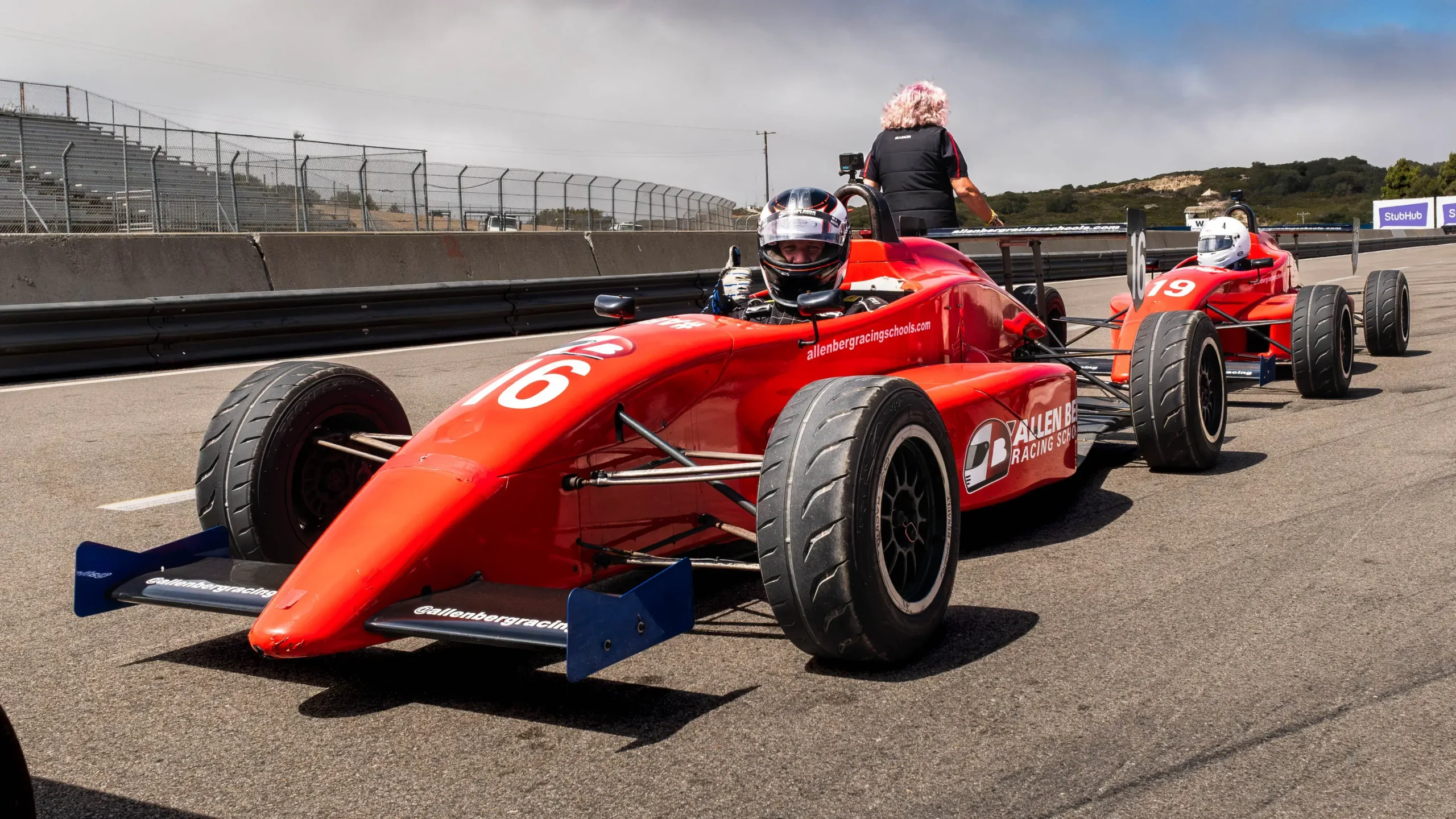 Low front angle of red open-wheel formula car number 16 sitting at the front of the pit lane lineup