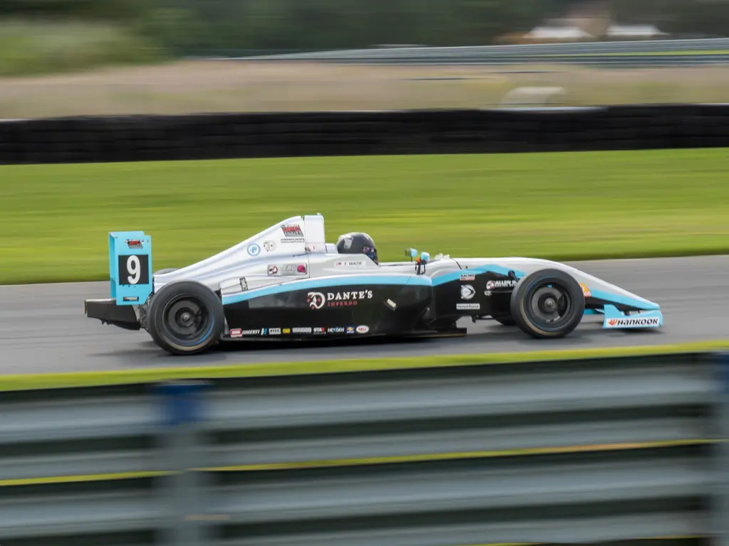 Tyler wade driving the number 9 dante's inferno berg racing car at high speed along the racetrack at vir.